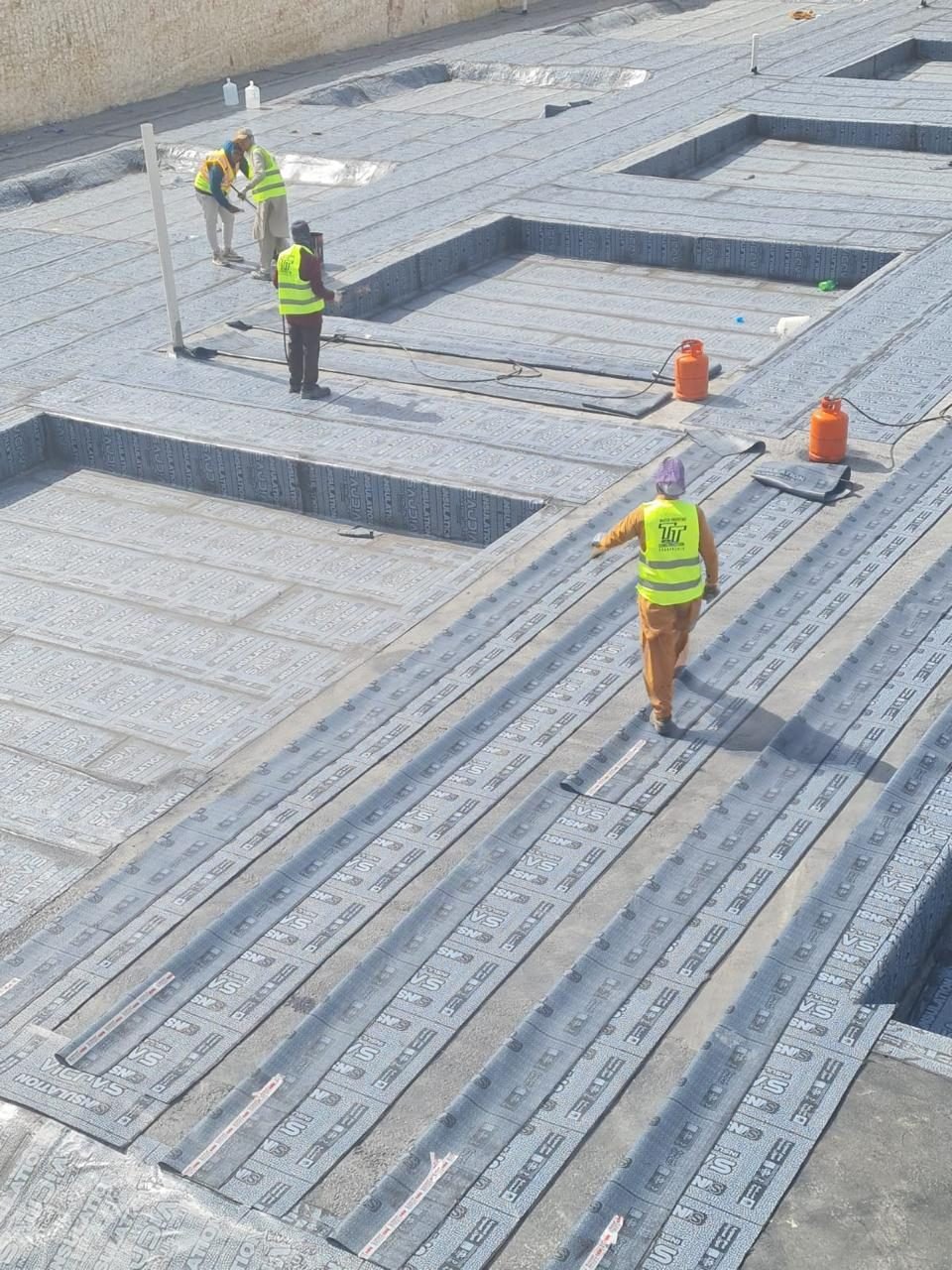 Waterproofing team inspecting a finished roof membrane